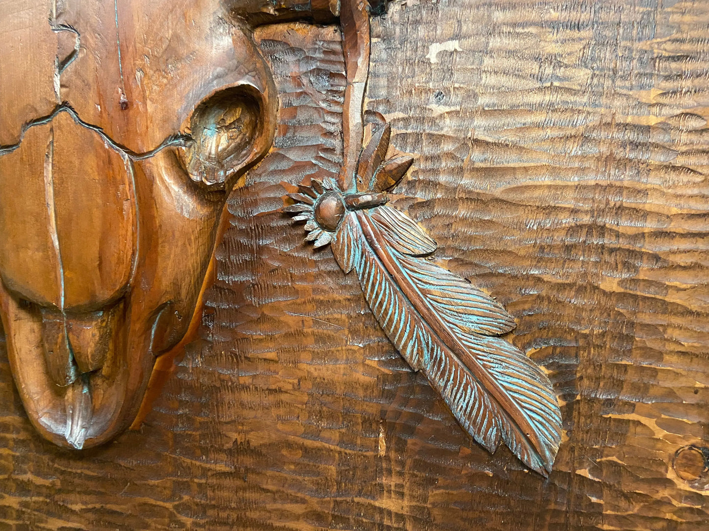 Close up front view of hand carved feather and cow skull