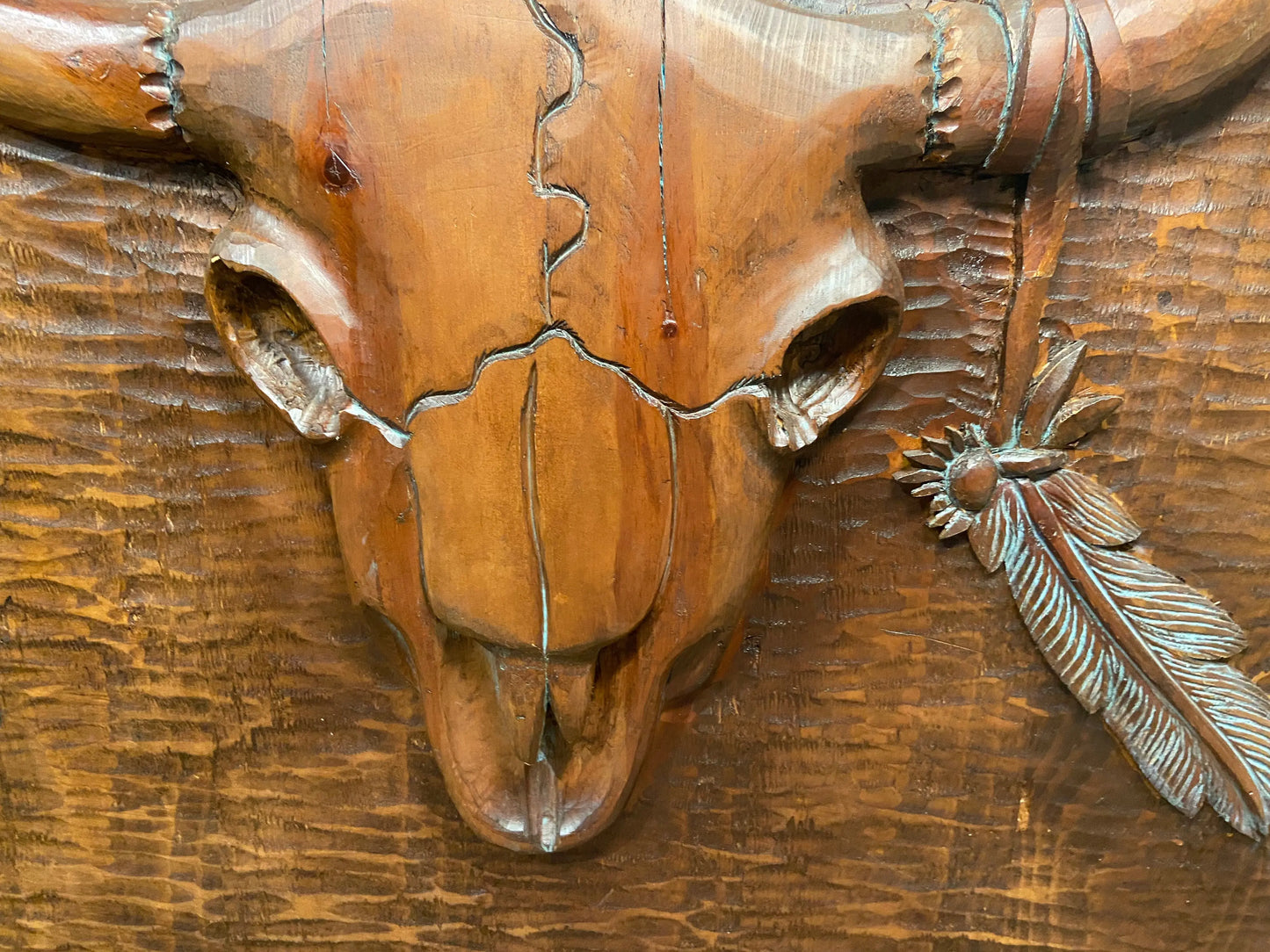 Close up of cow skull and feather. Shows details of hand carving.