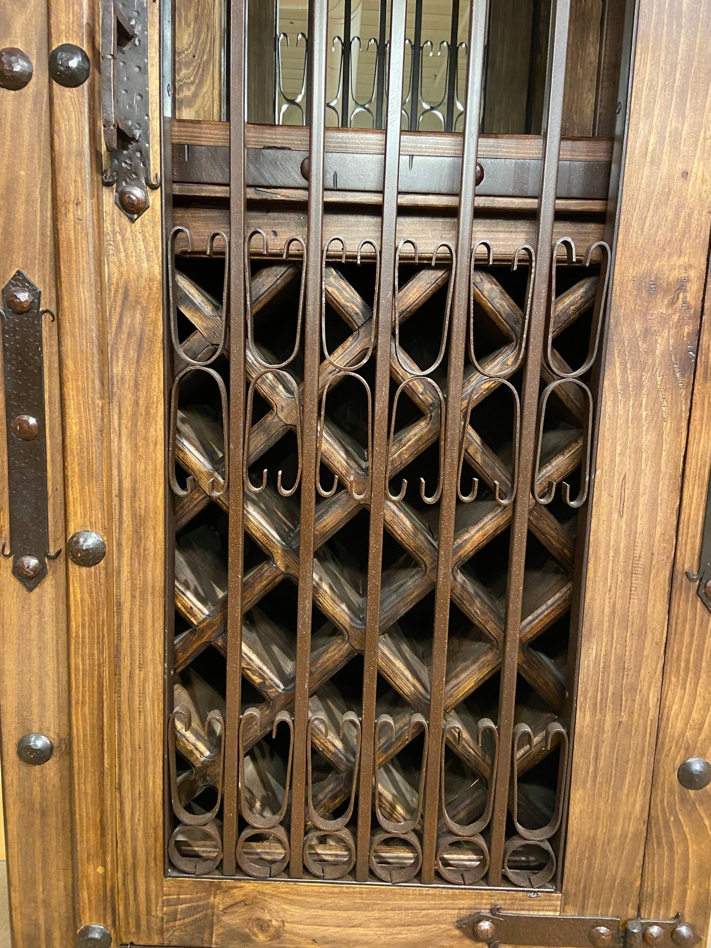 Front view of wine cabinet showing hand forged steel door closed in front of solid wood wine storage 