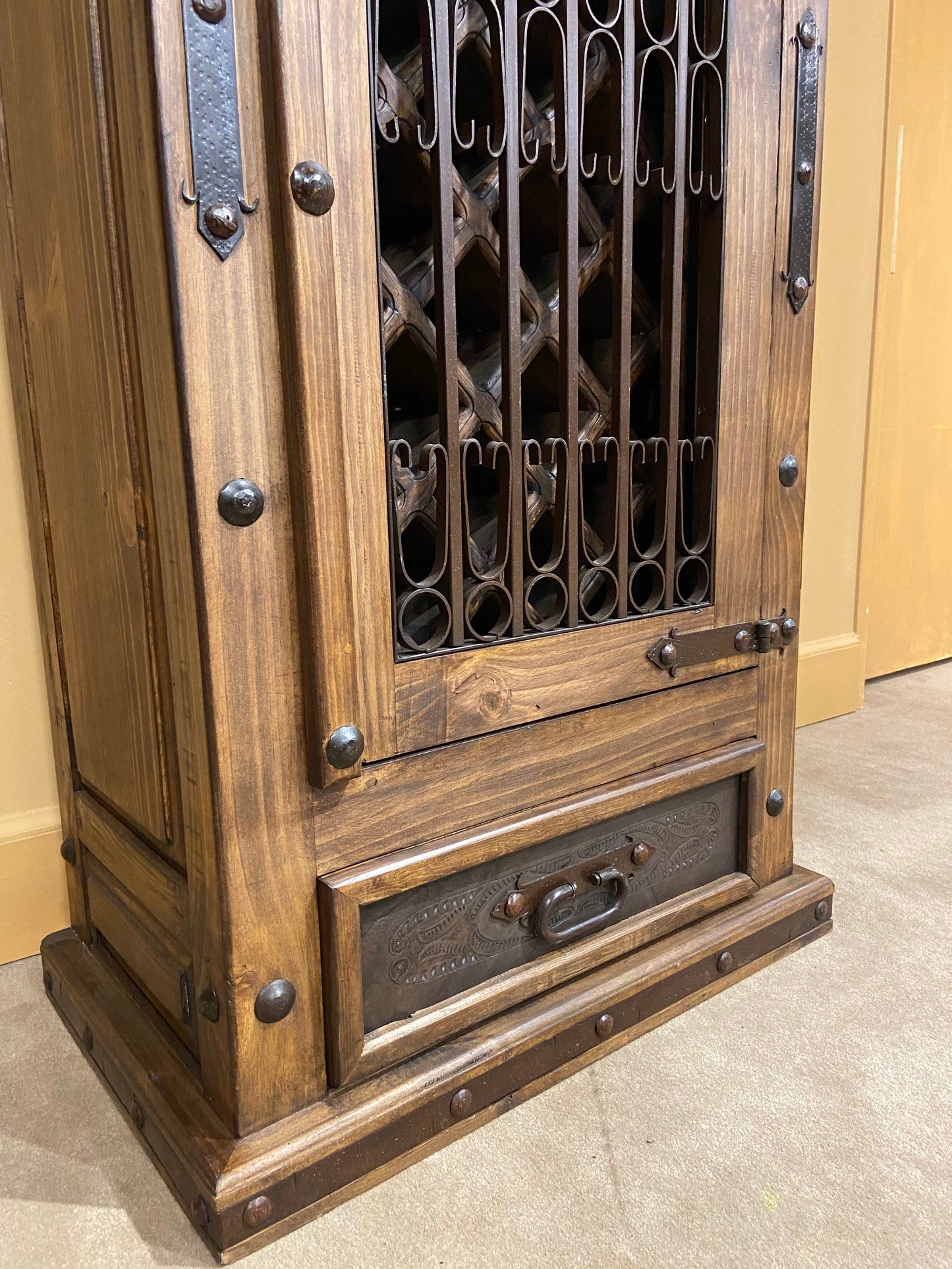 Bottom of wine cabinet showing hand forged steel elements and hand tooled leather on drawer