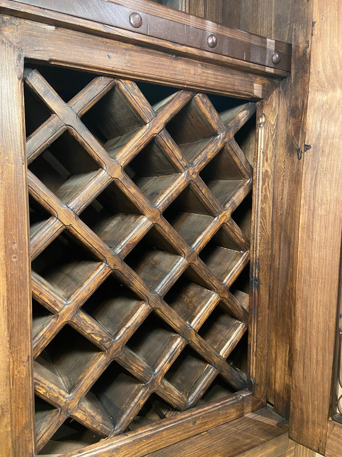 Close up of the solid wood wine bottle storage rack in the Tall Rustic Wine Cabinet.