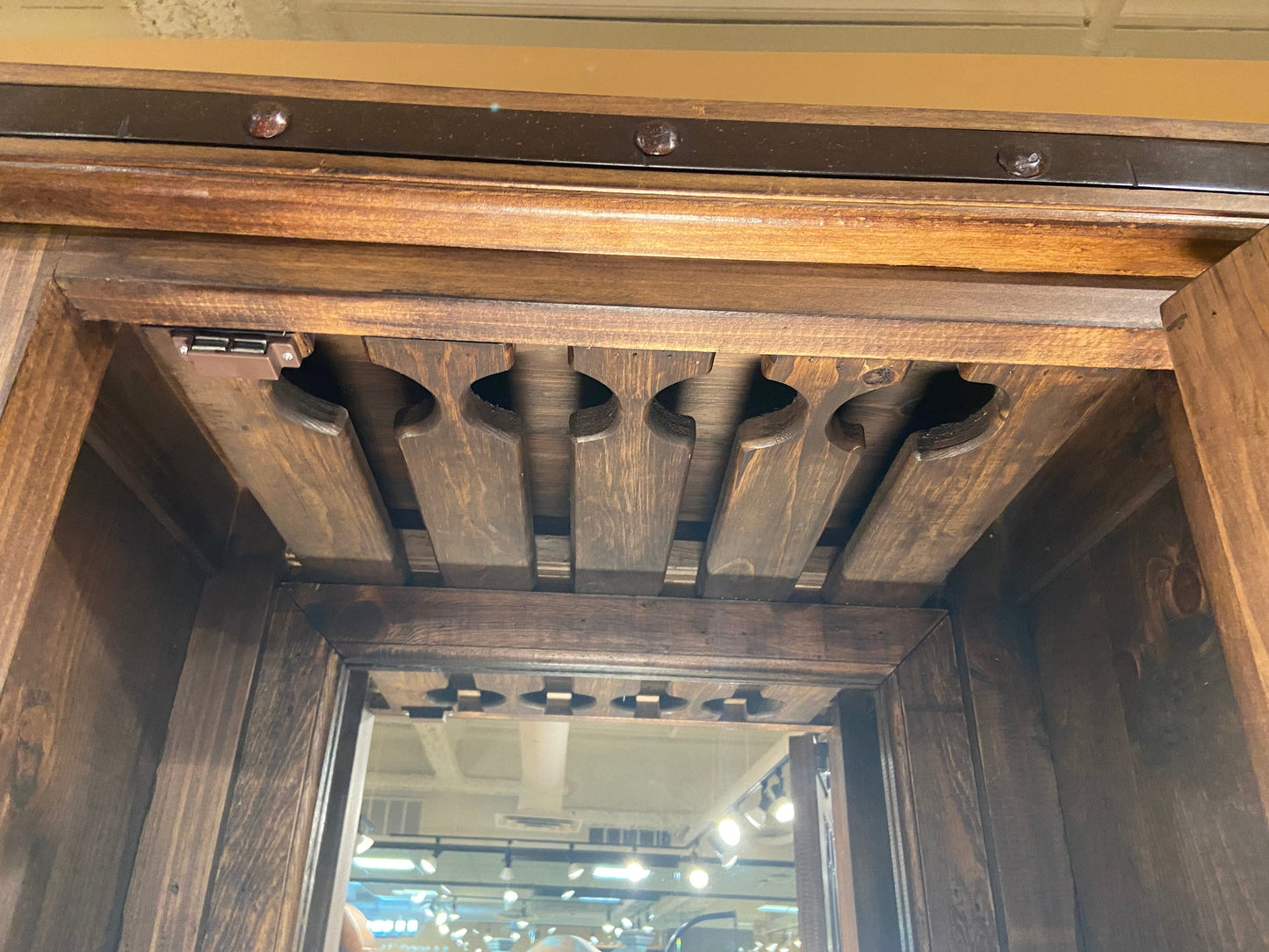 Close up of the solid wood stemware hanging rack above the mirror inside the wine bar. 