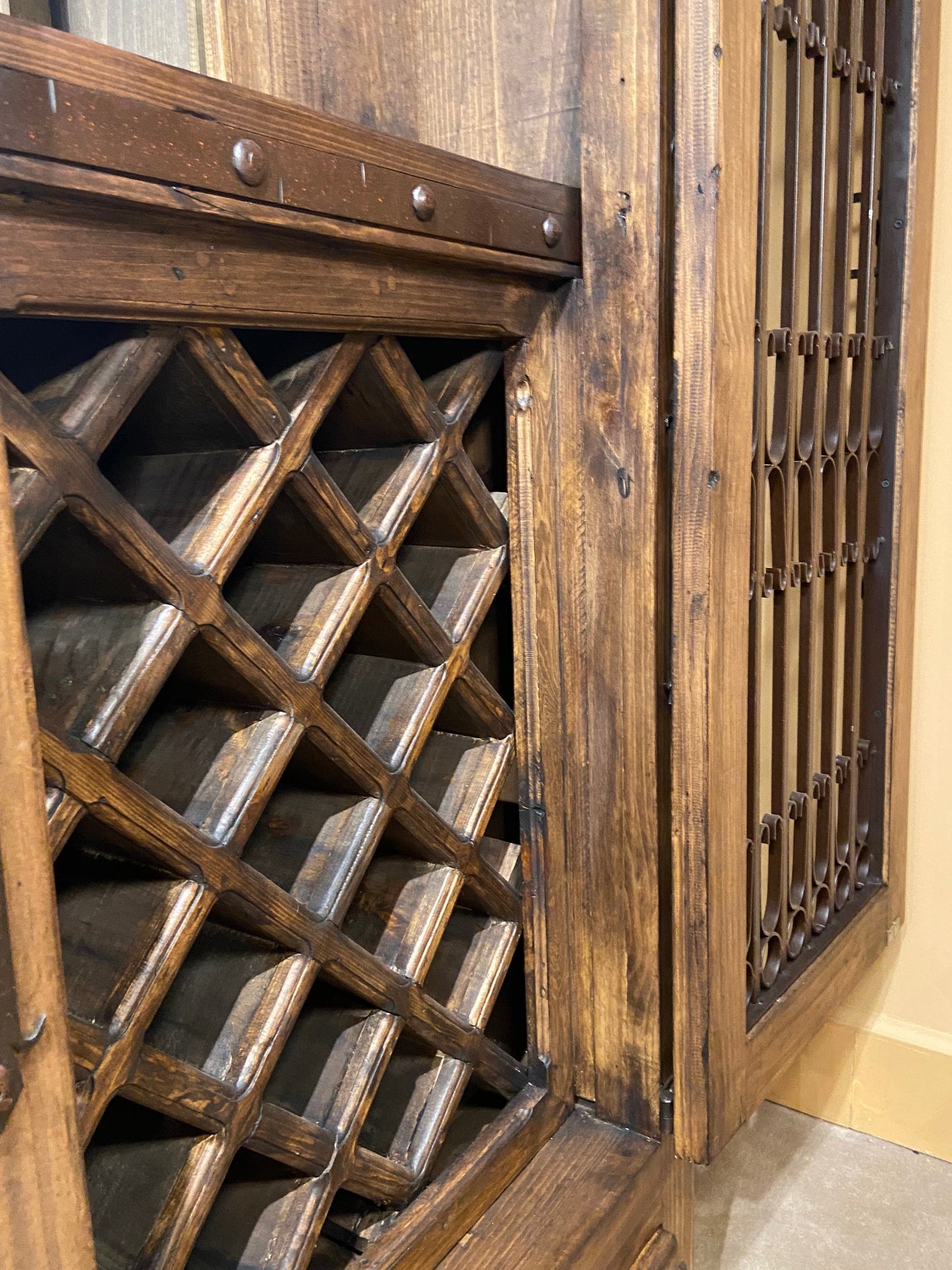 Close up of open door showing solid wood wine bottle storage. 